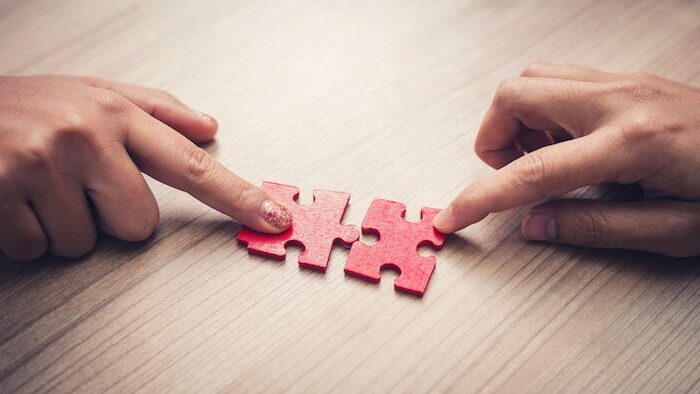 woman-hand-holding-jigsaw-puzzle-pieces-in-office